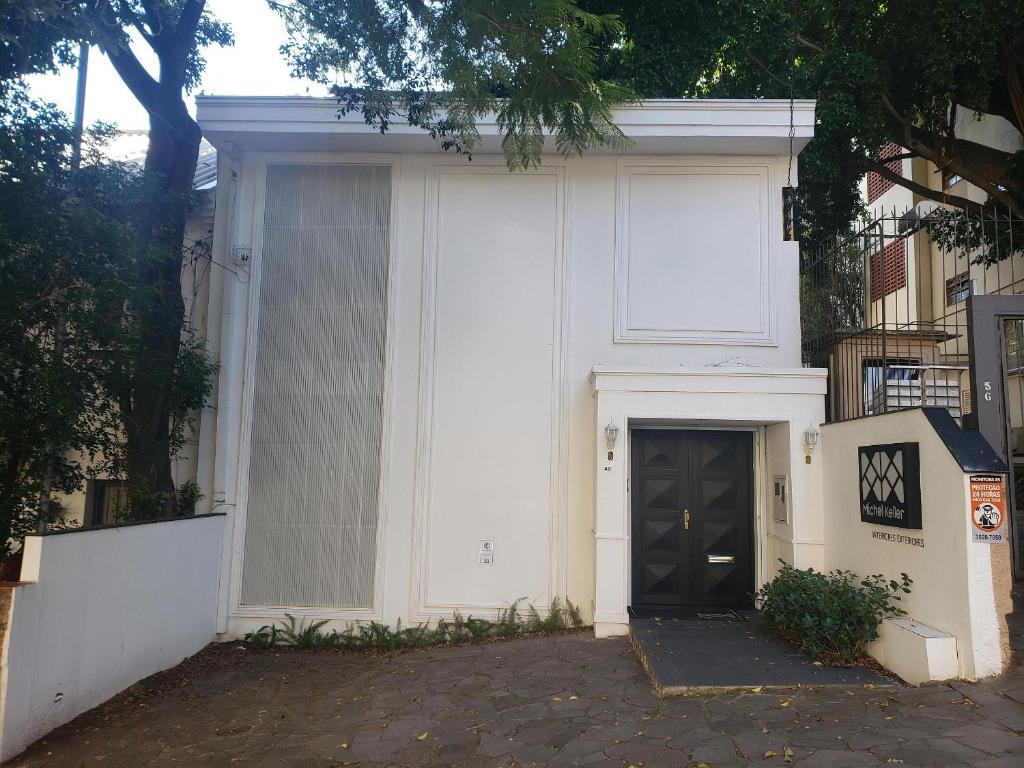 un edificio blanco con una puerta y un árbol en Casa Clássica no Mont Serrat, en Porto Alegre