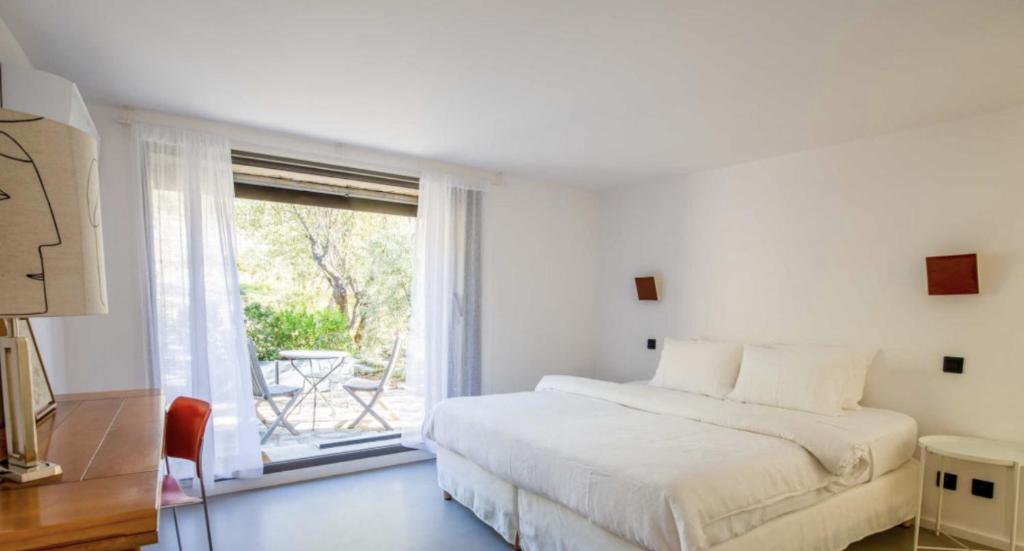 ein weißes Schlafzimmer mit einem Bett und einem großen Fenster in der Unterkunft l'Atelier des Milles Roches in Gordes