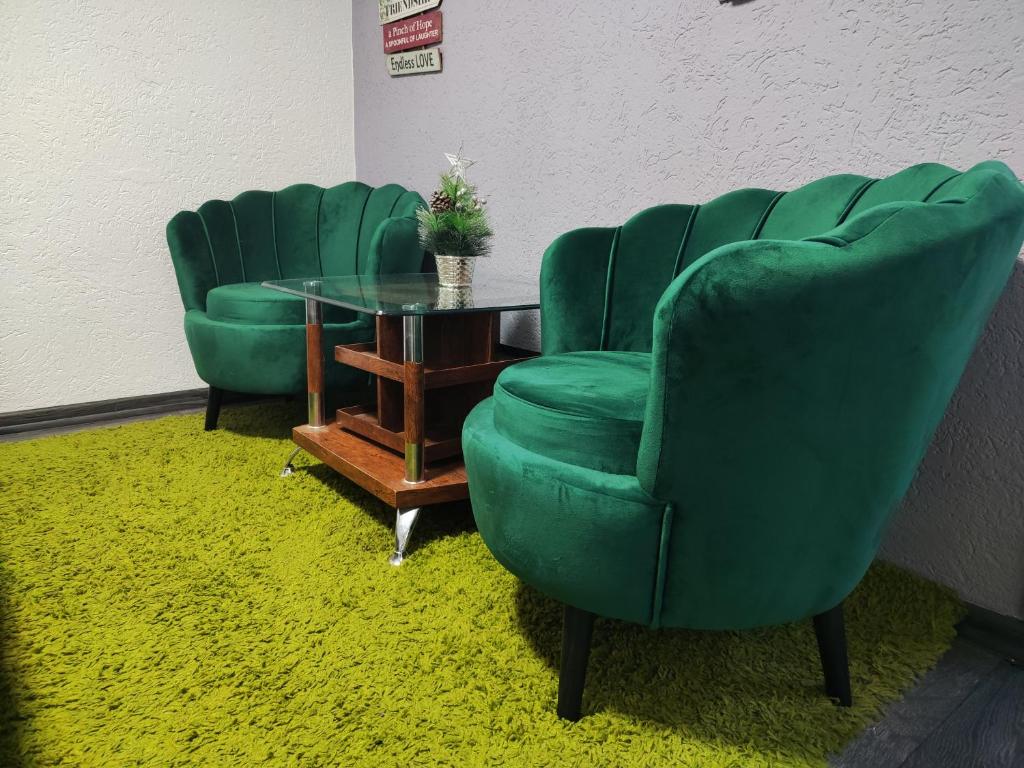 two green chairs and a table in a room at VINI studio with private parking in Skopje