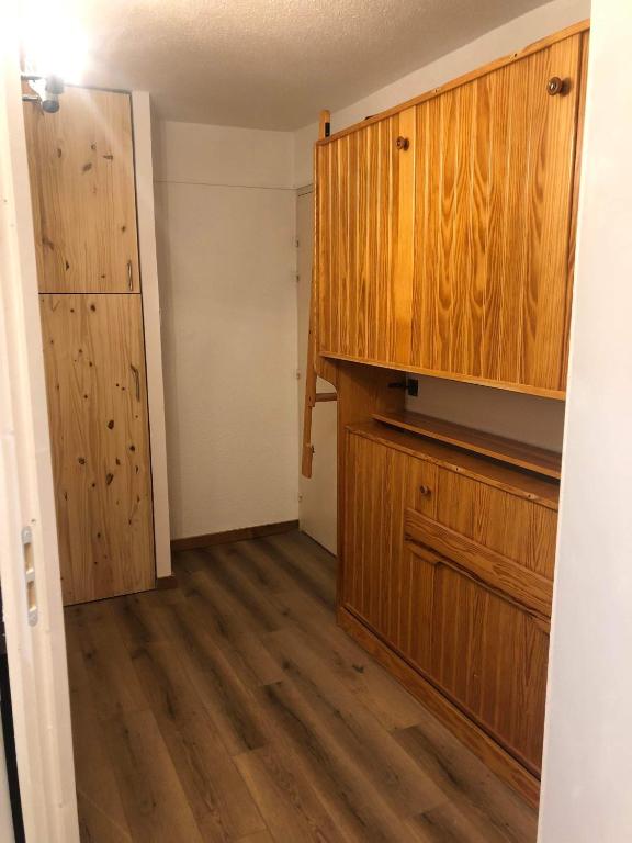 an empty room with a kitchen with wooden cabinets at Appartement Alpe-d&#39;Huez 4 Personnes in L&#39;Alpe-d&#39;Huez