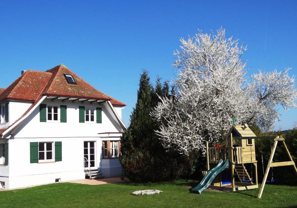 una casa con parque infantil frente a una casa en Schwarzwaldhaus24 - Ferienhaus mit Sauna, Whirlpool und Kamin, en Gemeinde Aichhalden