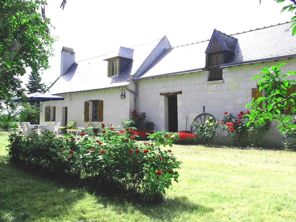 a white house with red flowers in front of it at La Maison Tournesol - 3 bedroom house with large garden near Saumur in Saint-Martin-de-la-Place