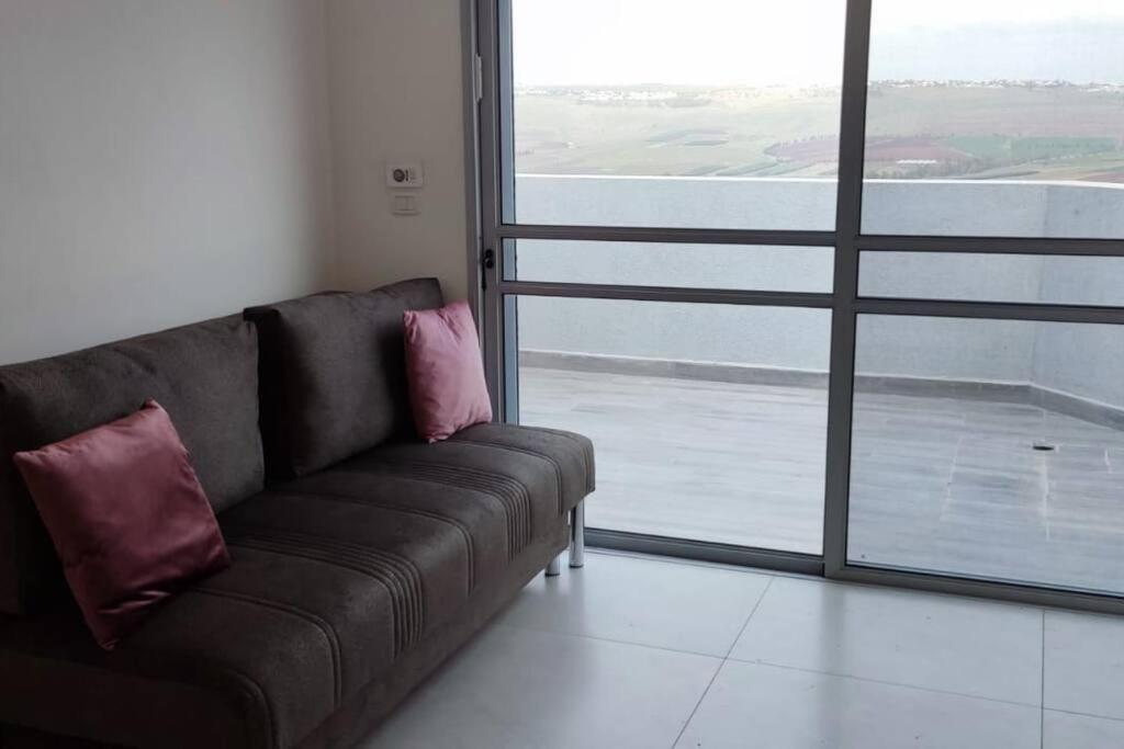un divano marrone in una camera con una grande finestra di צימר לזוג מתאים לדתיים בלבד a Yavneʼel