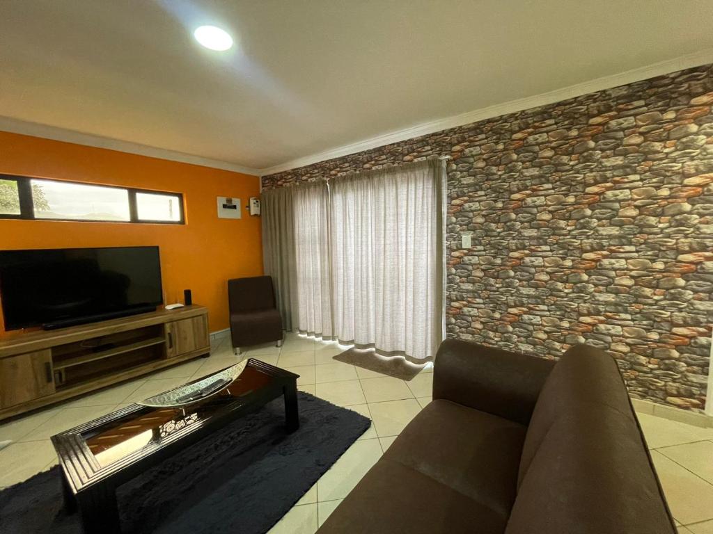 a living room with a couch and a stone wall at Cozy Inn in Tikoe