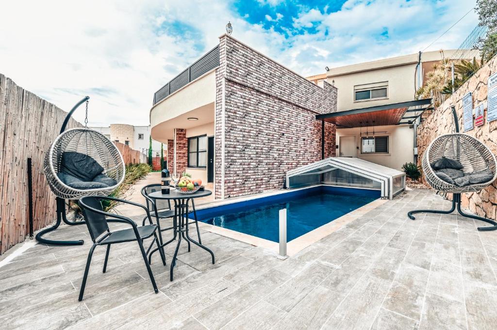 Dāliyat el KarmilにあるAnil's house - מתחם צימרים עם בריכה מקורה ומחוממת Zimmer with heated swimming poolのパティオ(椅子2脚付)、スイミングプールが備わります。