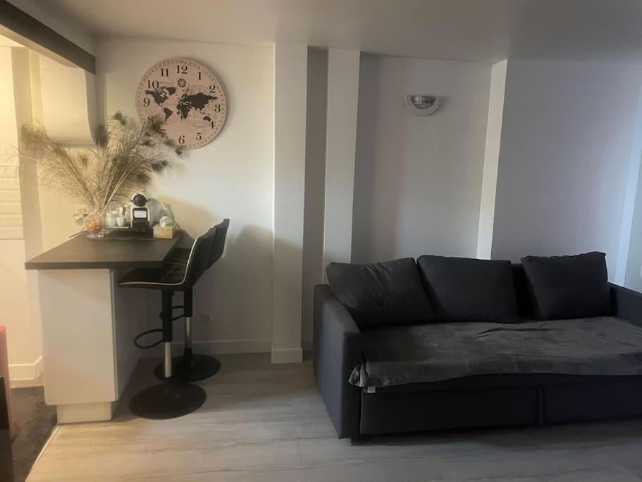 a living room with a couch and a clock on the wall at Studio centre Ville in Antony