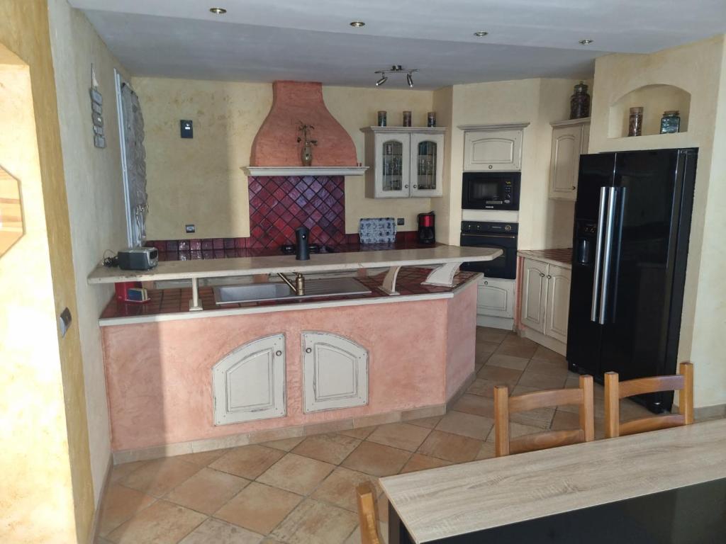 a kitchen with a black refrigerator and a counter top at CHAMBRE PRIVÉE EN CENTRE VILLe in Roissy-en-France