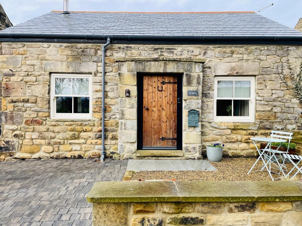 a stone house with a wooden door and a patio at The Parlour in Hexham