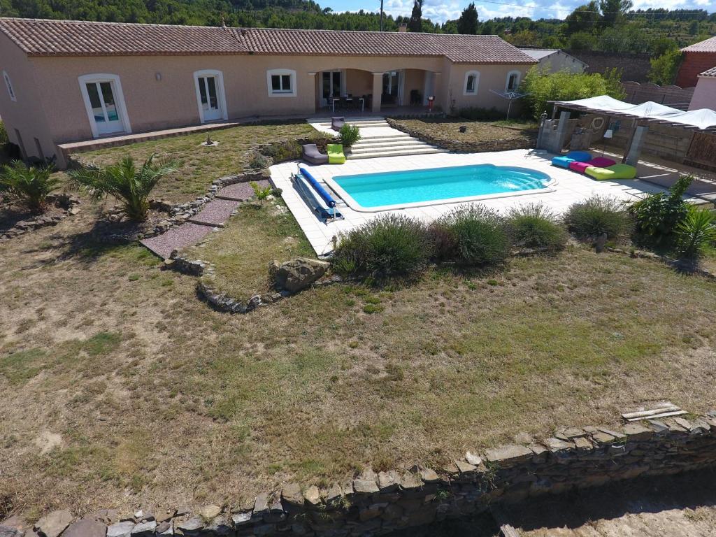 un patio trasero con piscina y una casa en B&B BonjourSoleil en Tourouzelle