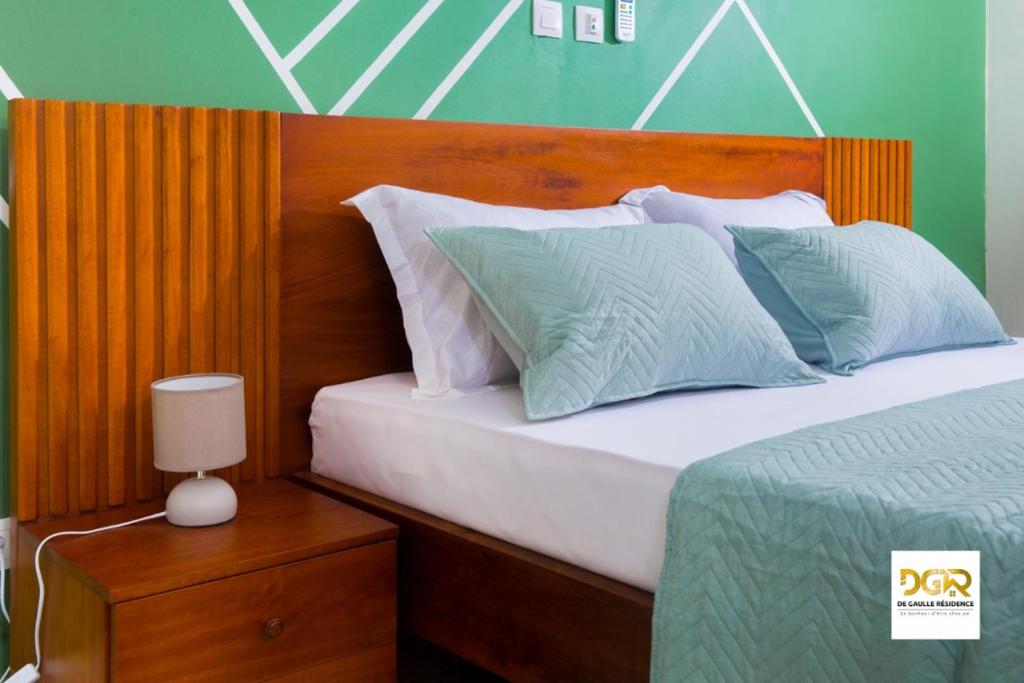 ドゥアラにあるDe Gaulle Residenceのベッド(木製のヘッドボード、枕付)