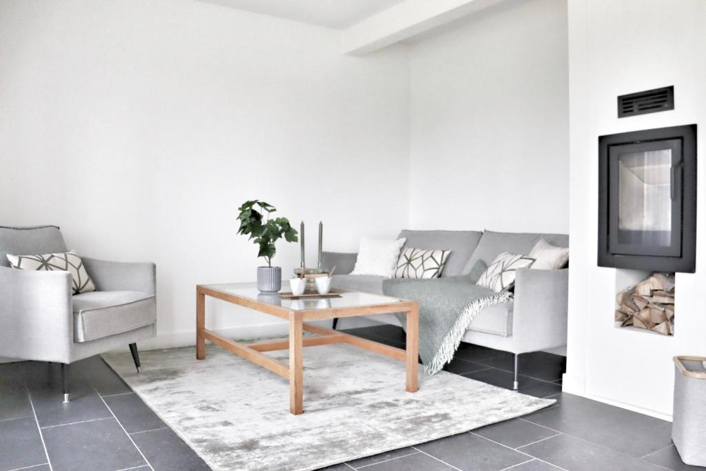 a living room with a couch and a table at Mysigt hus med kamin och pool in Torekov