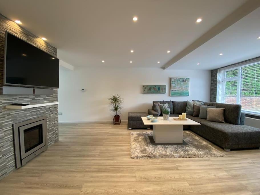 ein Wohnzimmer mit einem Sofa, einem Tisch und einem TV in der Unterkunft Msquared Villa, Modern 3-Bedroom House, 3 Parking Spaces in Kidlington