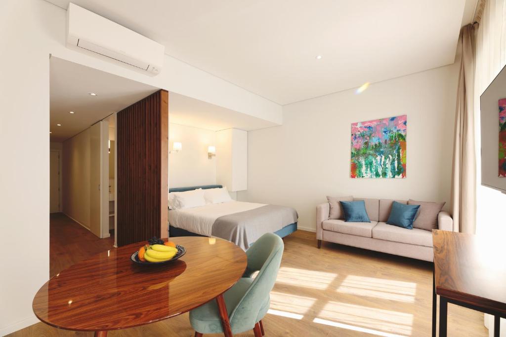 um quarto de hotel com uma mesa e uma cama e um sofá em RIBEIRA FLORES 59 Downtown Apartments em Porto