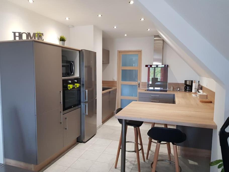 une cuisine avec un comptoir et une table avec des tabourets dans l'établissement Logement plein centre de Plérin à proximité des plages et des commerces, à Plérin