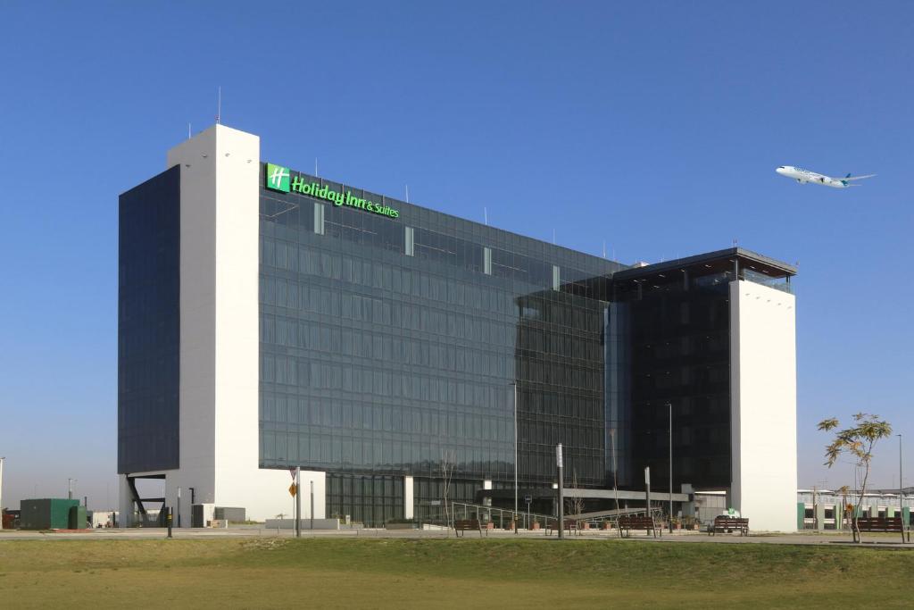 a large building with a green sign on it at Holiday Inn & Suites - Mexico Felipe Angeles Airport, an IHG Hotel in Zumpango de Ocampo