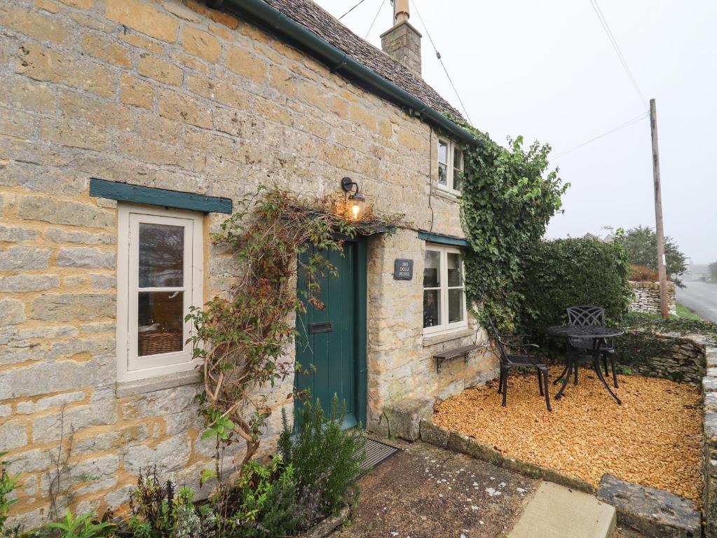 a stone cottage with a green door and a table at The Doll's House in Cheltenham