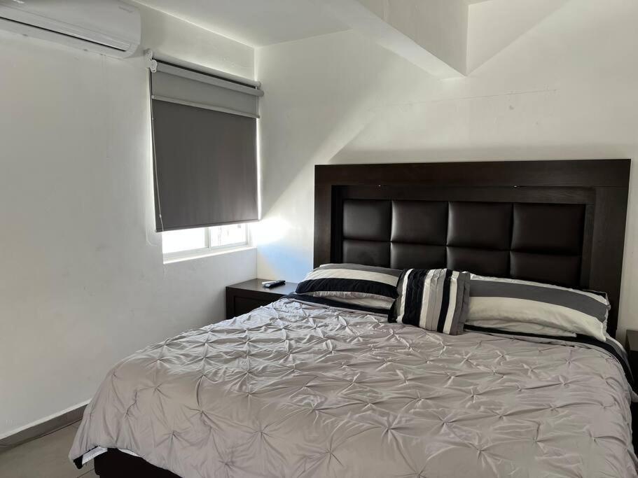 una camera con un grande letto e una finestra di Hermoso Dpto a pasos del Fashion Drive c/alberca a Monterrey