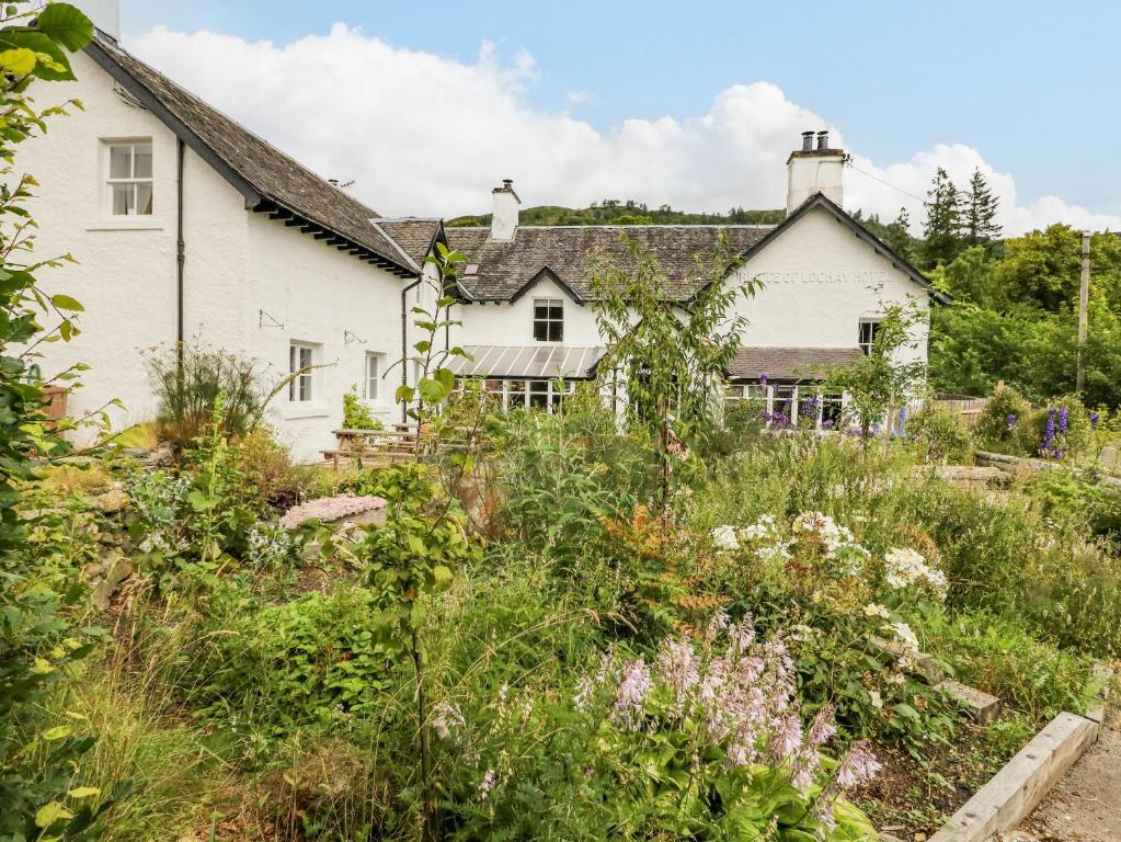 una casa blanca con un jardín delante de ella en The House at Bridge of Lochay, en Killin