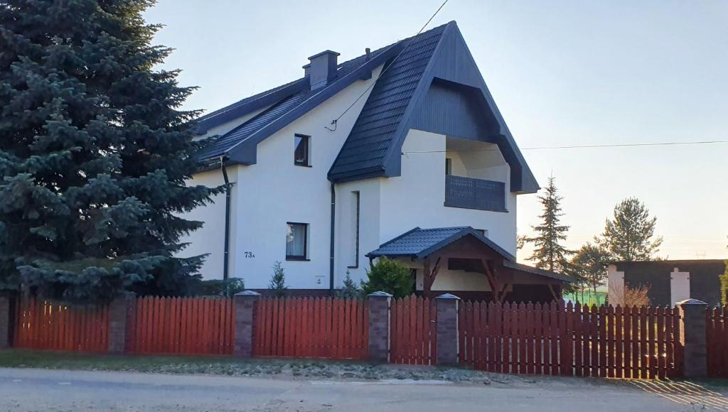 a white house with a red fence at Silence Villa in Szydłowice