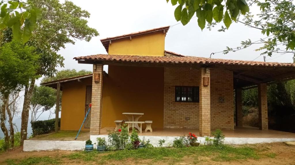 uma pequena casa com uma mesa em frente em Chalé Bella Vista em Guaramiranga