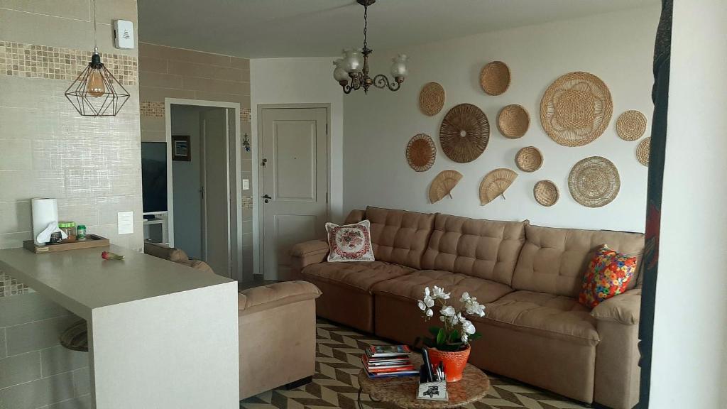 un soggiorno con divano e piatti appesi al muro di AMPLA COBERTURA NA PRAIA DO MAR GROSSO LAGUNA a Laguna