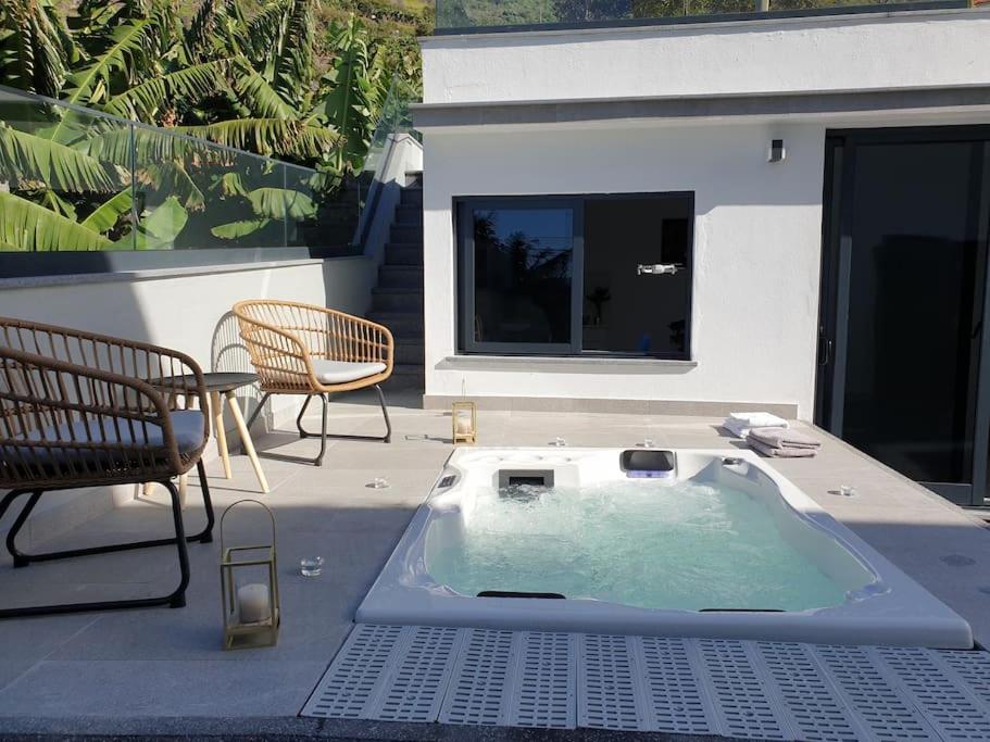a hot tub sitting on a patio with two chairs at Sunset Avenue for couple w/ jacuzzi spa hot water in Paul do Mar