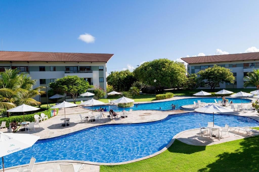 una vista aérea de una piscina del complejo con mesas y sombrillas en Apartamento Carneiros Beach Resort en Tamandaré