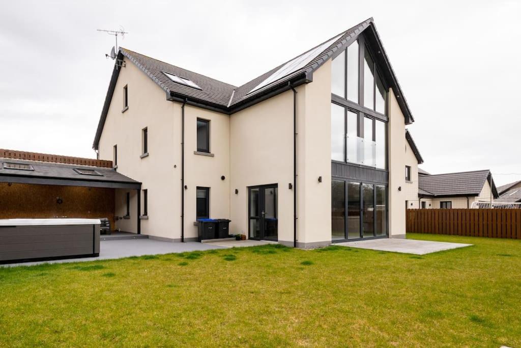 a large white house with a lawn in front of it at Modern house with hot tub, perfect night away! in Huntly