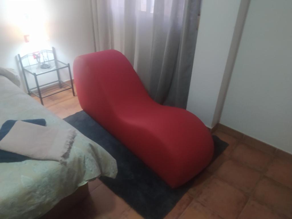 a red chair sitting in a room next to a bed at Paraiso Huertano in Alquerías