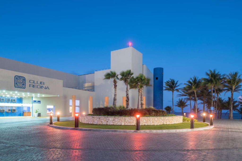 a building with palm trees and lights in front of it at Club Regina Cancun in Cancún