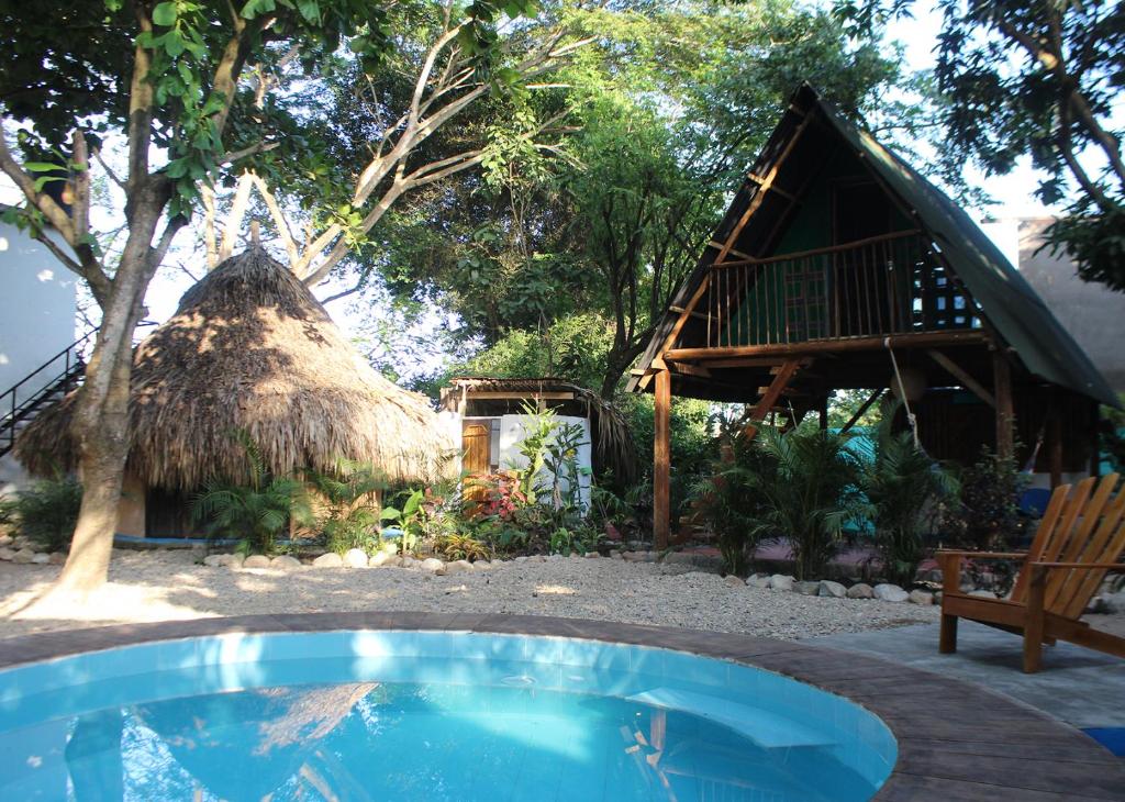 a resort with a small pool and a thatch hut at Los Almendros Palomino Hostel in Palomino