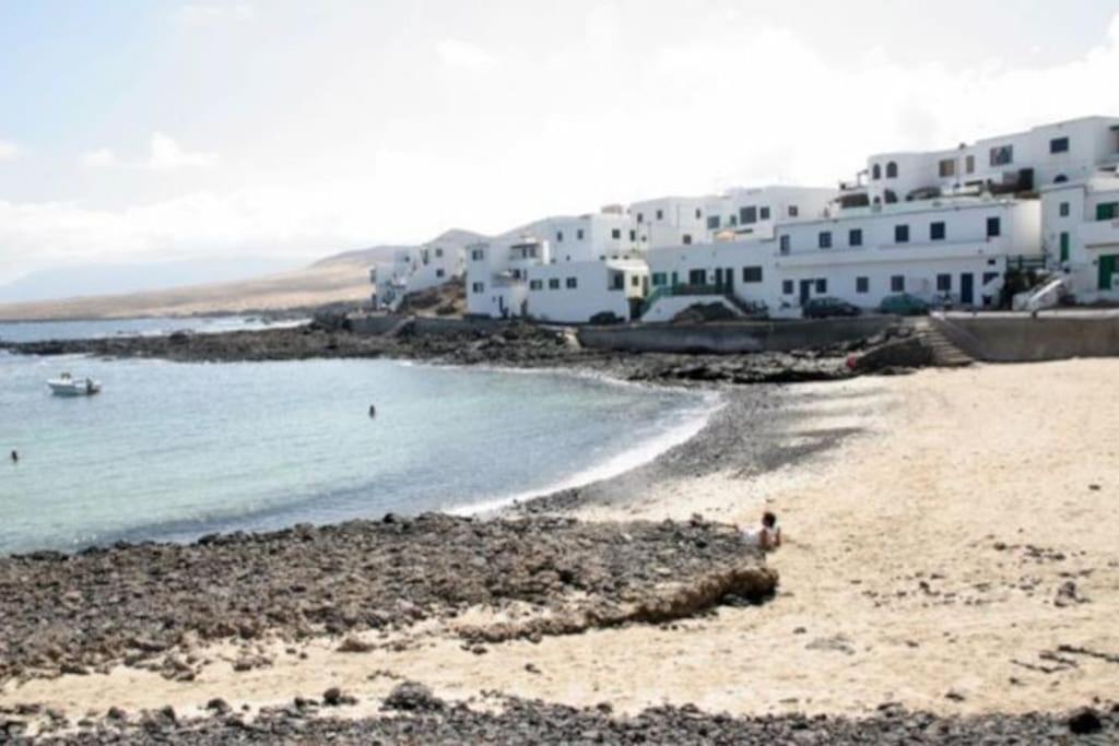 a beach with a group of white buildings and the ocean at Casa Caleta Caballo in Caleta de Caballo