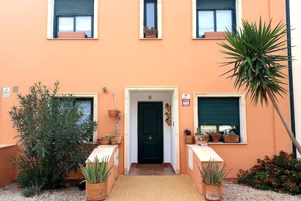 een oranje huis met een zwarte deur en wat planten bij Casa La Hojiblanca in Mancha Real