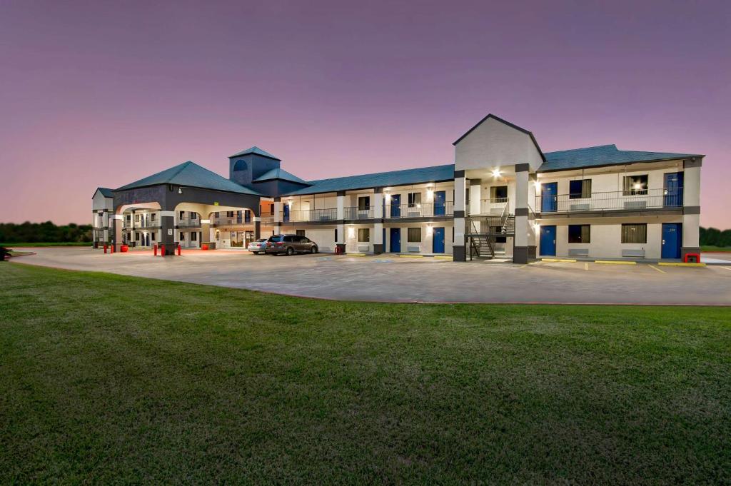 a large building with a car parked in a parking lot at Studio 6 - Texas City, TX in Texas City