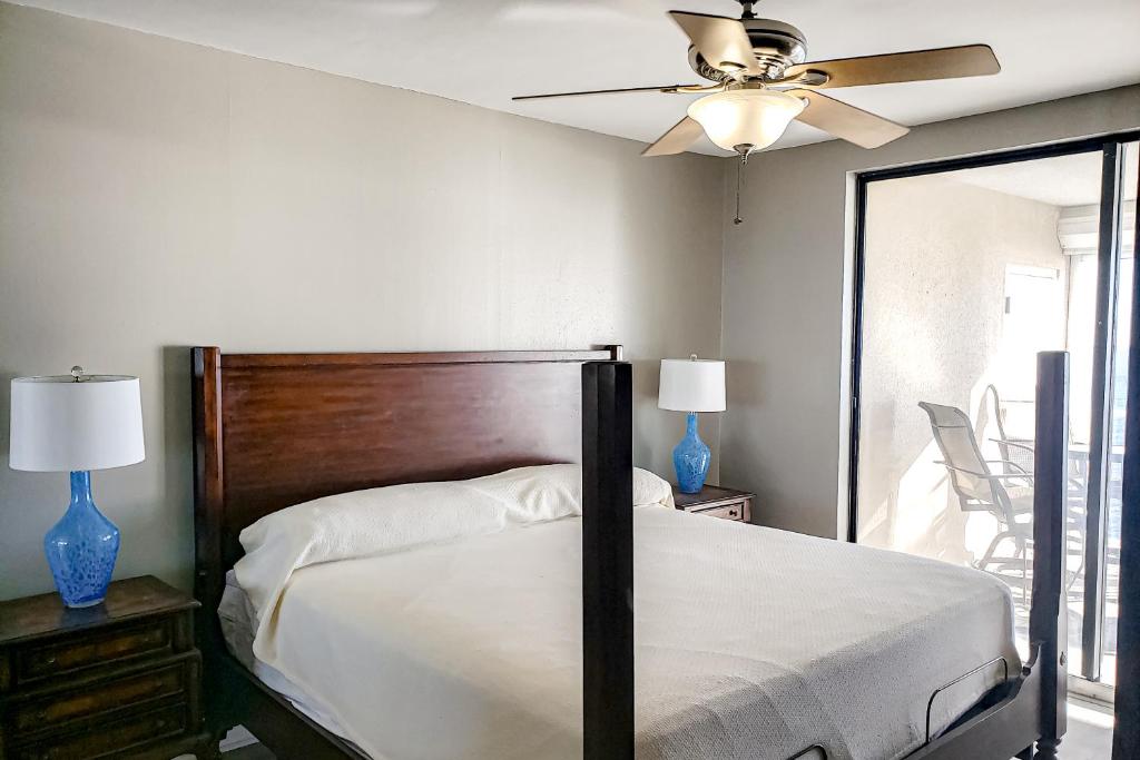 een slaapkamer met een bed, een plafondventilator en een spiegel bij Bluewater 1504 in Orange Beach