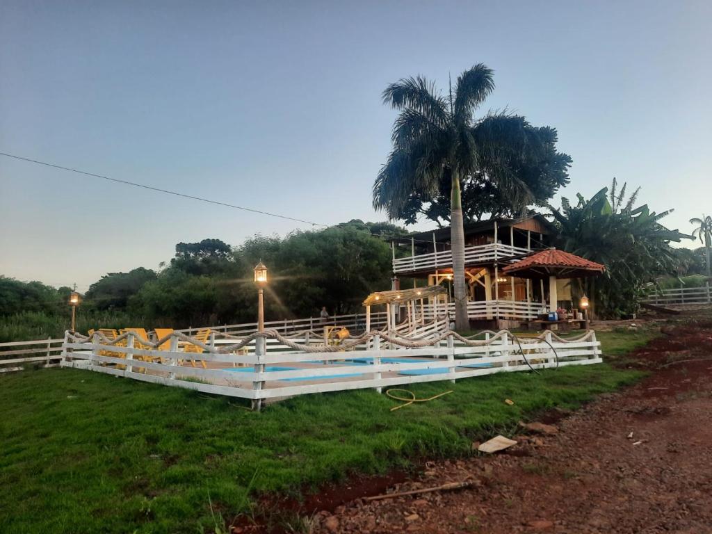 a house with a palm tree and a white fence at A casa da arvore no Parana 