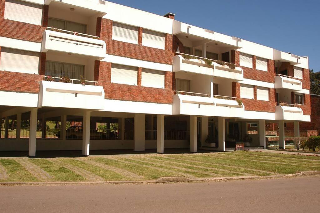 un grande edificio in mattoni con un prato di fronte di Apartamento 2 dormitorios en Arcobaleno a Punta del Este