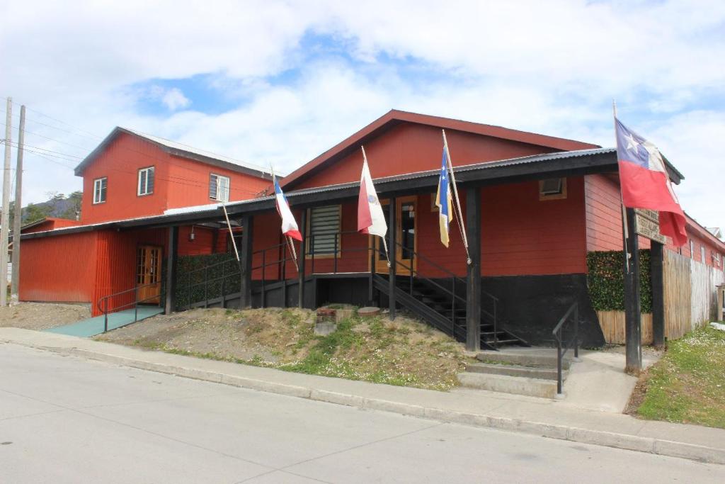 a red building with flags in front of it at Hotel Forjadores del Cabo de Hornos in Puerto Williams
