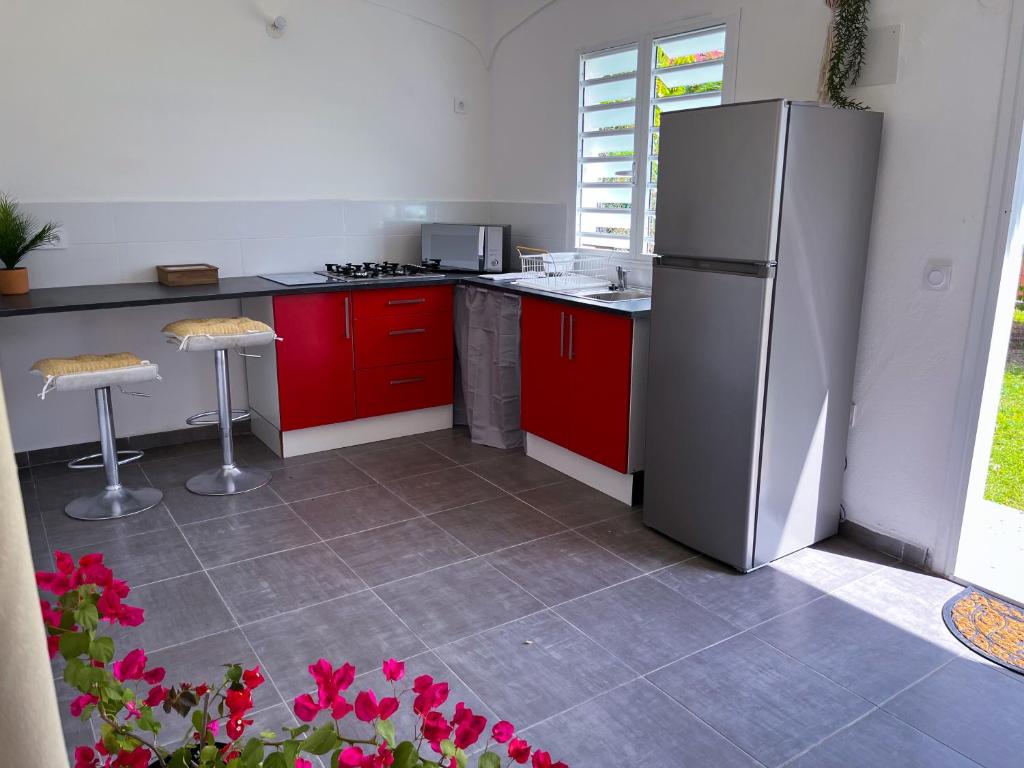 a kitchen with red cabinets and a stainless steel refrigerator at T2 Paisible et spacieux in Baie-Mahault