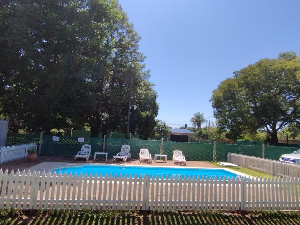 una valla blanca que rodea una piscina con tumbonas en Cabañas Eterno Vergel en Mburucuyá