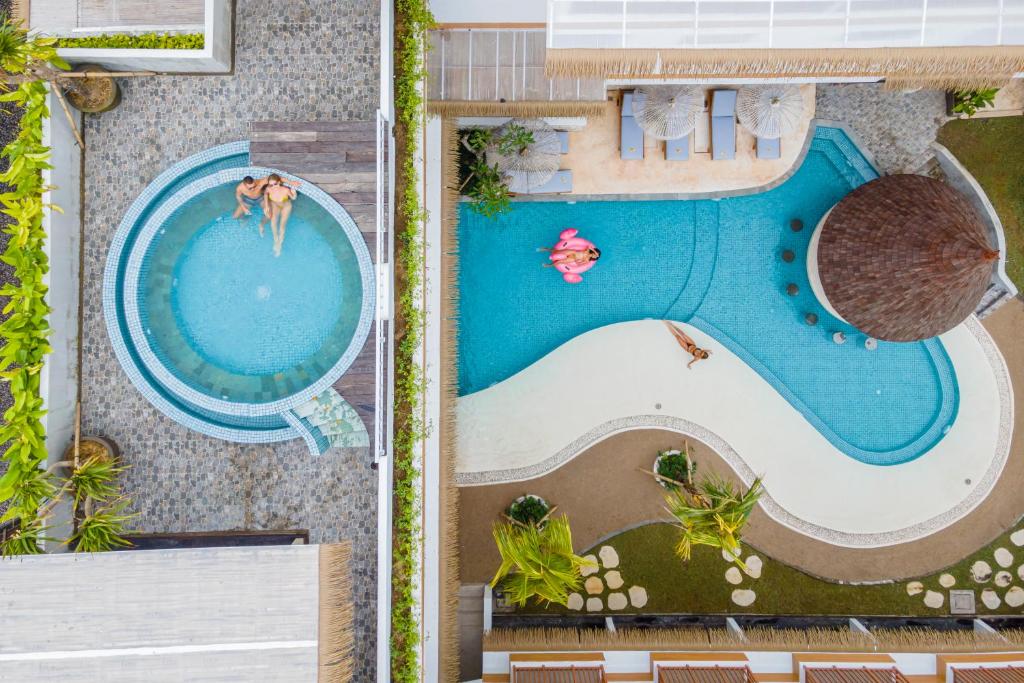 an overhead view of a swimming pool with two people in it at Roomates Hostel Canggu by Ini Vie Hospitality in Canggu