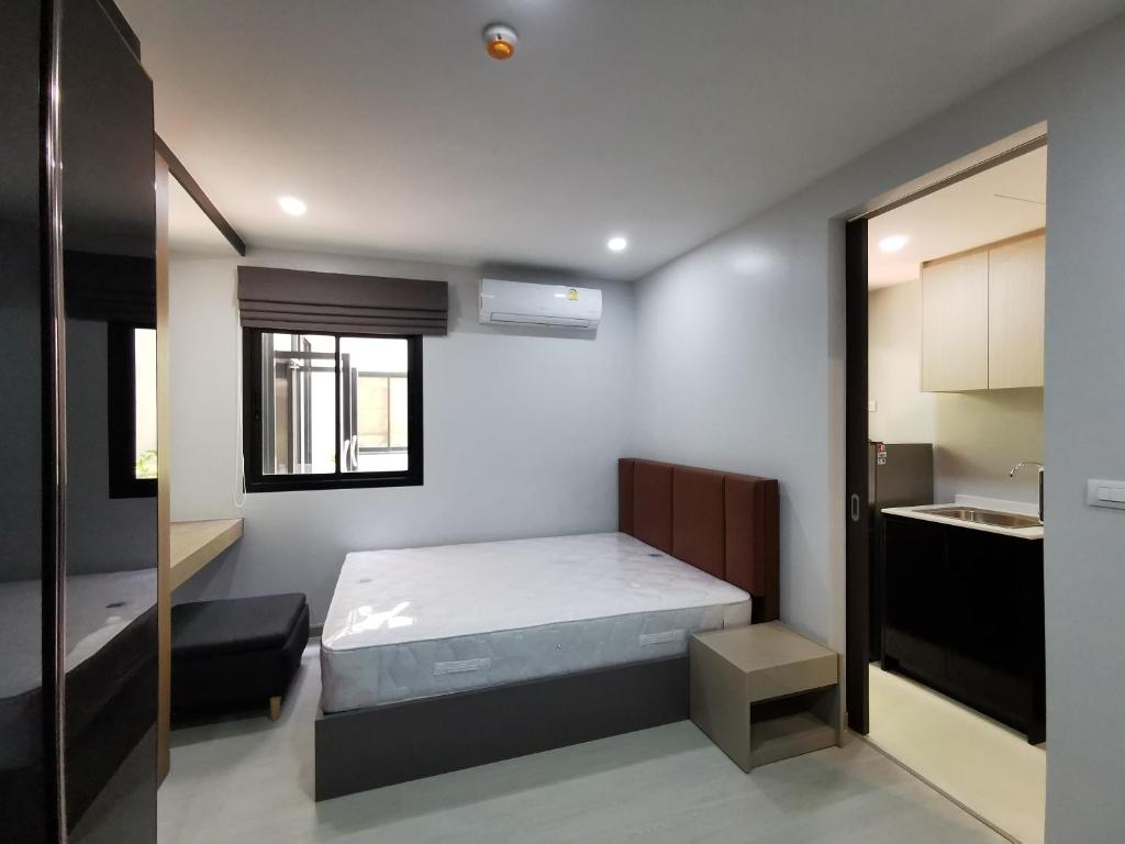 een kleine slaapkamer met een bed en een keuken bij VIP Great Hill in Thalang