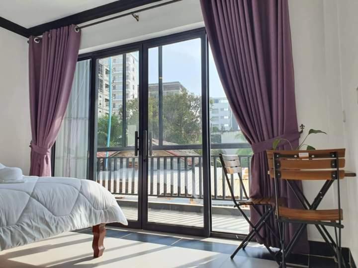 a bedroom with a bed and a balcony with purple curtains at Paradise Cozy Guesthouse Sihanoukville in Sihanoukville