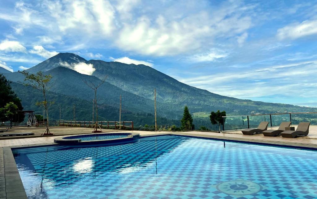 a swimming pool with a mountain in the background at Alinson Sunset Hill in Bogor