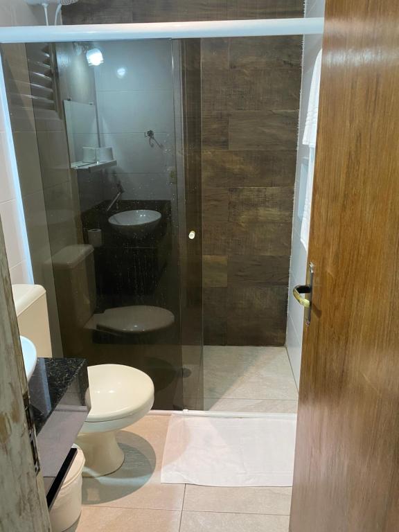 uma casa de banho com um WC e uma porta de duche em vidro. em Flat 102 em Riviera de São Lourenço