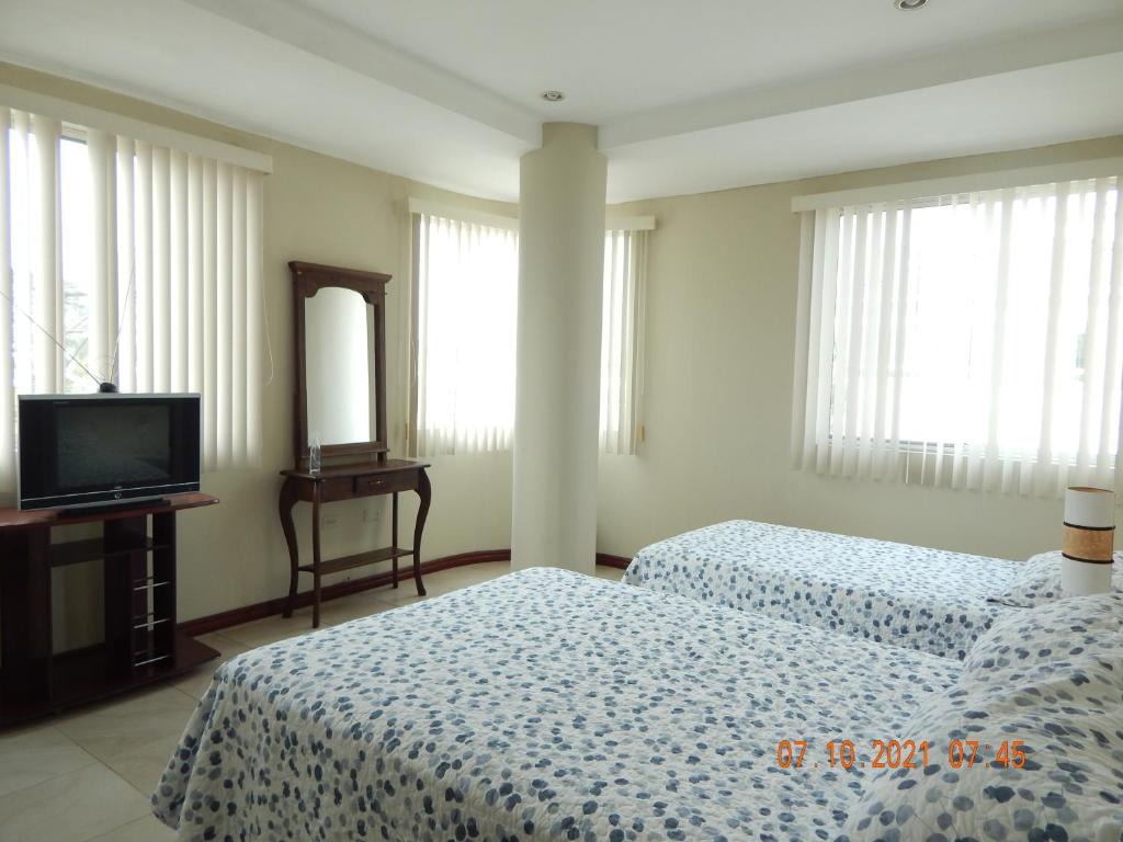 Habitación de hotel con 2 camas y TV en SUITE DORAL ¡¡CERCA DEL AEROPUERTO!!, en Guayaquil