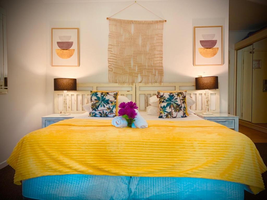 a bedroom with a yellow bed with flowers on it at Ramada Resort - Stylish Deluxe Apartment in Port Douglas