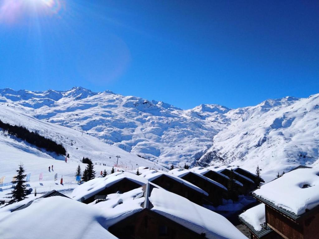 une montagne enneigée avec un lodge de ski en avant dans l'établissement Résidence Les Alpages de Reberty - maeva Home - Appartement 3 pièces 6 personnes Selection MAE-6459, aux Menuires