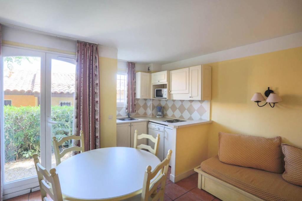 une cuisine avec une table, des chaises, une table et une fenêtre dans l'établissement Les Issambres Bellevue - maeva Home - 2 Pièces 5 Personnes Budget MAE-1206, aux Issambres