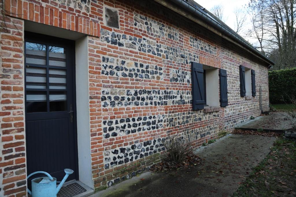 uma casa de tijolos com uma porta preta e uma parede de tijolos em Grange du Tôt em Fontenay